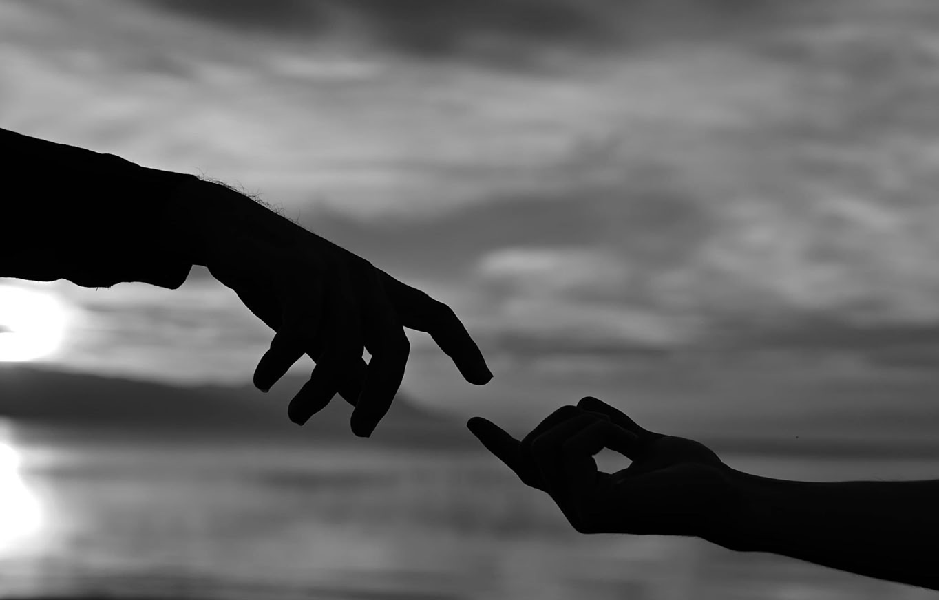 Künstlerische Schwarz-Weiß-Silhouette zweier sich bei Sonnenuntergang berührender, ausgestreckter Hände.